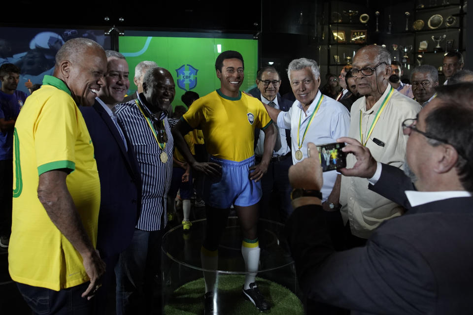 Former Brazilian soccer legends, from left, Dario, Rogerio Caboclo (the president of the Brazilian Football Confederation ), Edu, Clodoaldo and Brito. pose for a photo with a statue of soccer legend Pele at the Brazilian Soccer Team Museum in Rio de Janeiro, Brazil, Thursday, Feb. 20, 2020. The Brazilian Football Confederation unveiled the statue as part of commemorations of 50 years since the World Cup victory in 1970. (AP Photo/Leo Correa)
