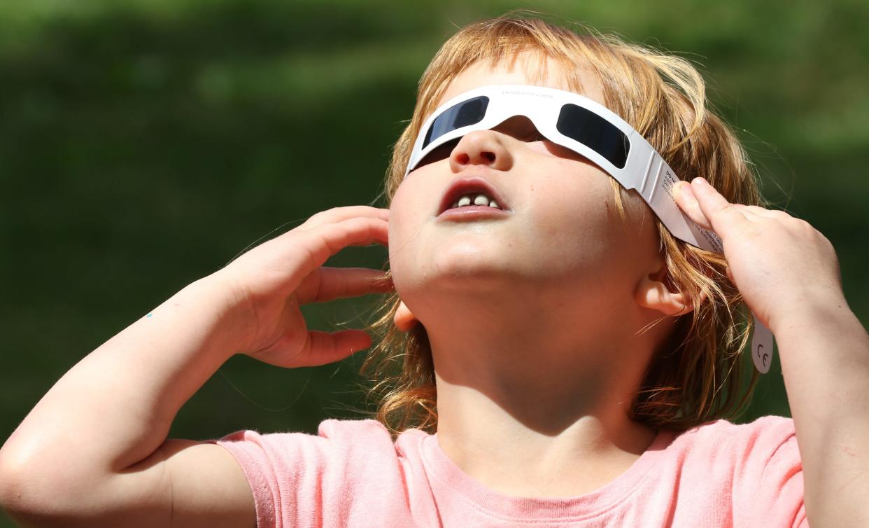 Four-year-old Autumn Joy checks out the eclipse as people gathered to watch Monday afternoon, April 8, 2024, at the Gateway Trail in Kings Mountain.