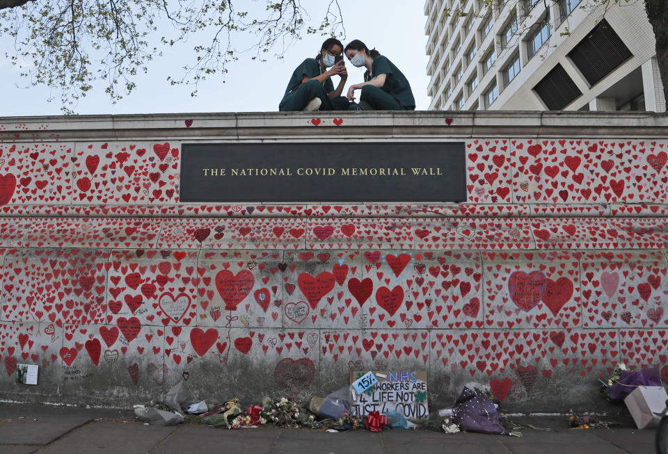 FILE - In this Tuesday, April 27, 2021 file photo, nurses from the nearby St Thomas' hospital sit atop the National Covid Memorial Wall in London. British Prime Minister Boris Johnson has on Wednesday, May 12 confirmed that an independent public inquiry into the government’s handling of the coronavirus pandemic will start hearing evidence next year. While welcoming the announcement, a leading group representing the bereaved think it should begin sooner. (AP Photo/Frank Augstein, file)