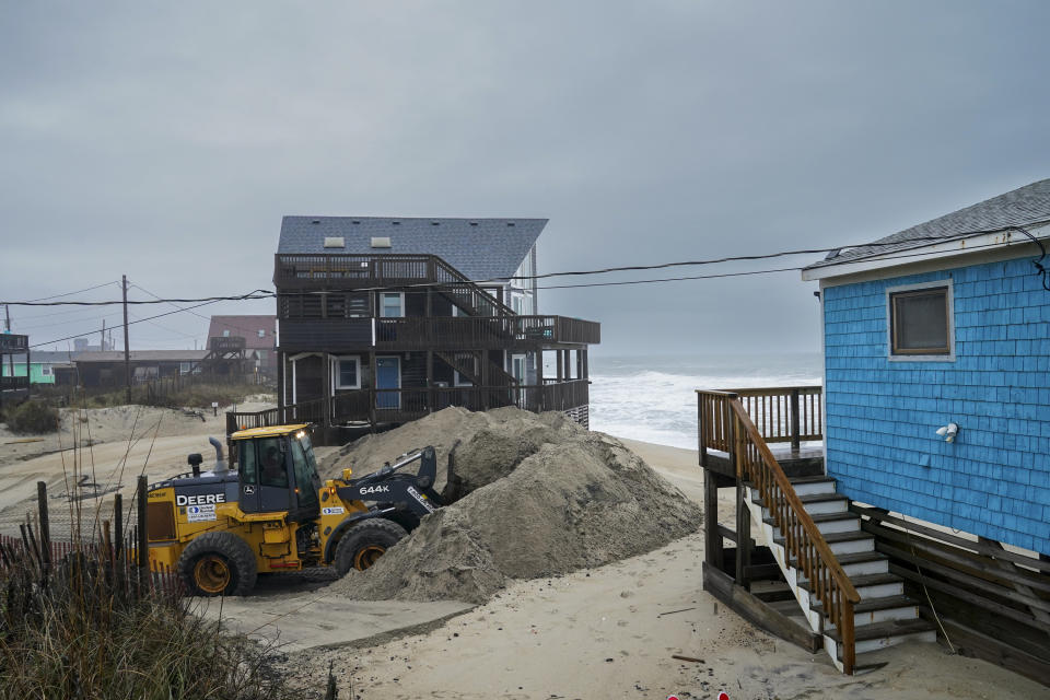 A worker from the North Carolina Department of Transportation clears ocean-driven sand from Surfside Drive on North Carolina's Outer Banks.