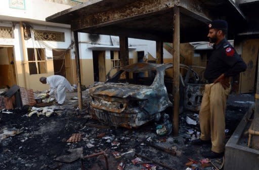 A Pakistani policeman stands next to the wreckage of a burnt car at a school that was set fire by an angry mob, following a protest alleging the school gave a test that insulted the Prophet Mohammed, in Lahore on November 2, 2012. Blasphemy is an extremely sensitive issue in Pakistan, where 97 percent of the population are Muslims