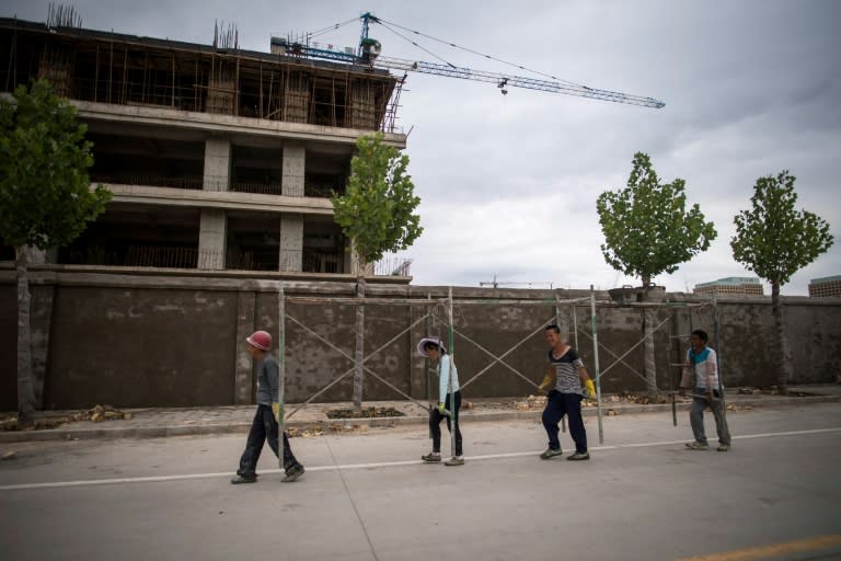 Workers carry scaffolding past a construction site in a development called 'Shenzhen City' on the outskirts of Kashgar in China's western Xinjiang province