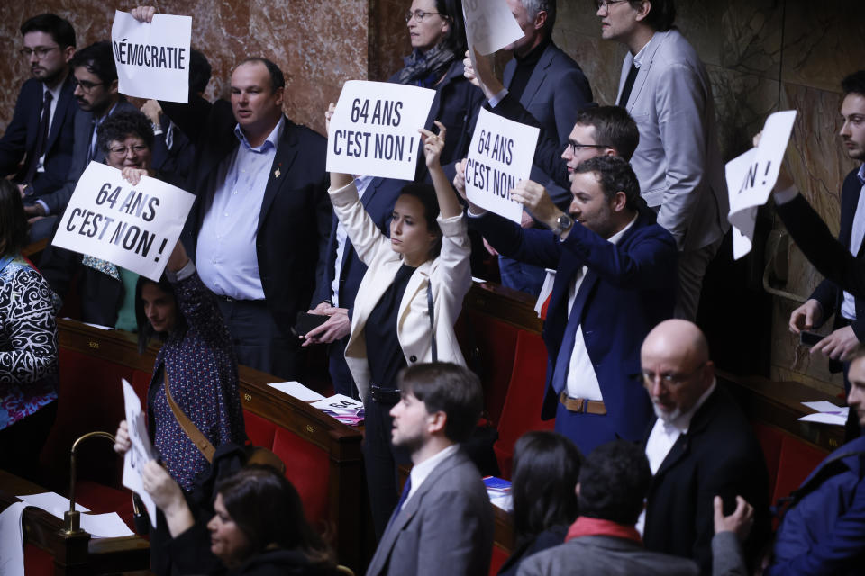 Far-left lawmakers react as they hold papers reading: «64 years. It is no» at the National Assembly in Paris, Thursday, March 16, 2023. France's government on Thursday invoked a special constitutional power to enact a contentious pension bill without a vote in parliament. The decision was made just a few minutes before the vote was scheduled because the government had no guarantee that the bill would command a majority at the National Assembly, France's lower house of parliament. (AP Photo/Thomas Padilla)