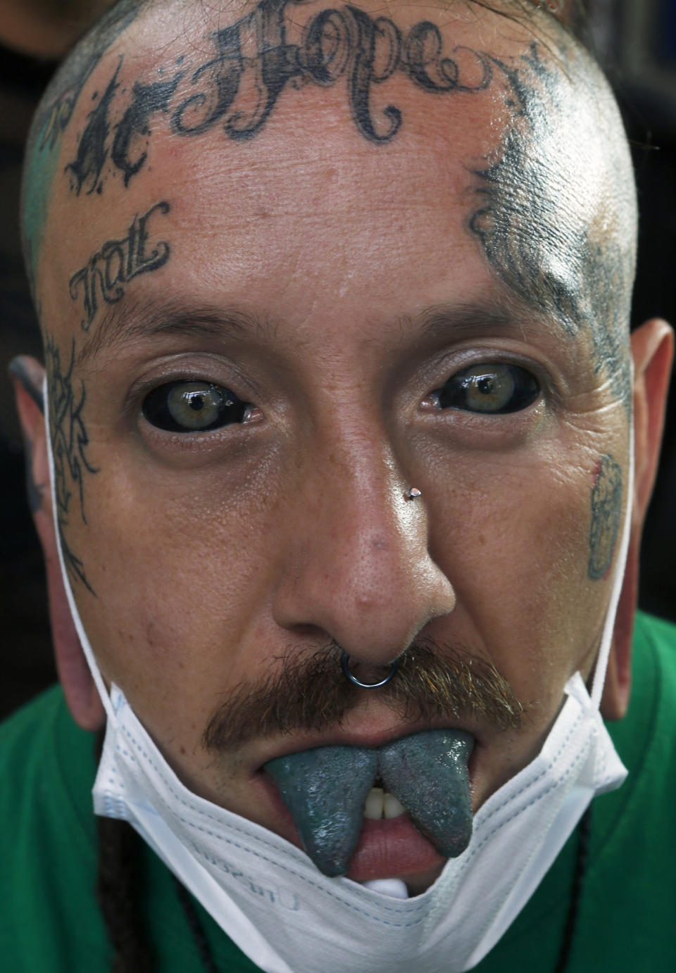 En esta foto del 18 de abril de 2019, Ariel Guzmán, también conocido como el artista del tatuaje Fakundo, muestra sus globos oculares tatuados, su lengua dividida y verde tatuada, orejas y nariz perforadas, así como varios tatuajes de su cabeza en el salón de tatuajes Corona en la Ciudad de México. (AP Foto / Marco Ugarte)