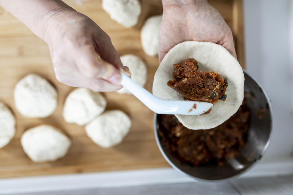 Stuffing steamed bun dough with pork.