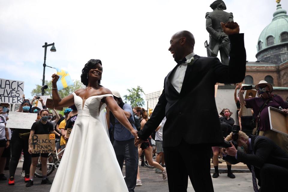 FILE - In this June 6, 2020, file photo, Kerry Anne Perkins and Michael Gordon came out to the crowd during a protest, Saturday, June 6, 2020, in Philadelphia over the death of George Floyd. The couple realized amid the pandemic they would have to cancel their wedding but wound up having a microwedding. As they did their first look, a massive Black Lives Matter demonstration arrived at Philadelphia's Logan Square. Photos of the couple holding hands, fists raised, with thousands of people surrounding them went viral. (Tyger Williams/The Philadelphia Inquirer via AP, File)