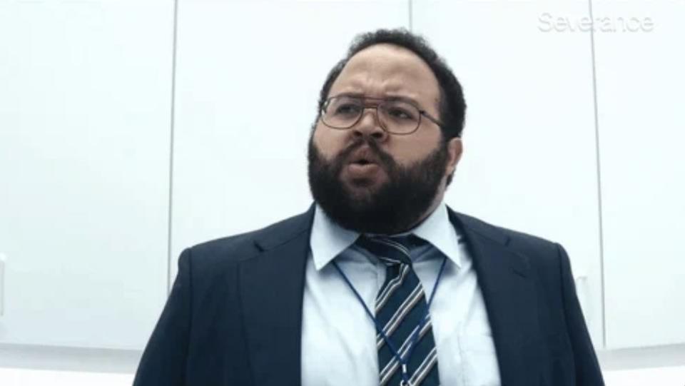 A man with glasses and a beard, wearing a suit and tie, appears to be confused