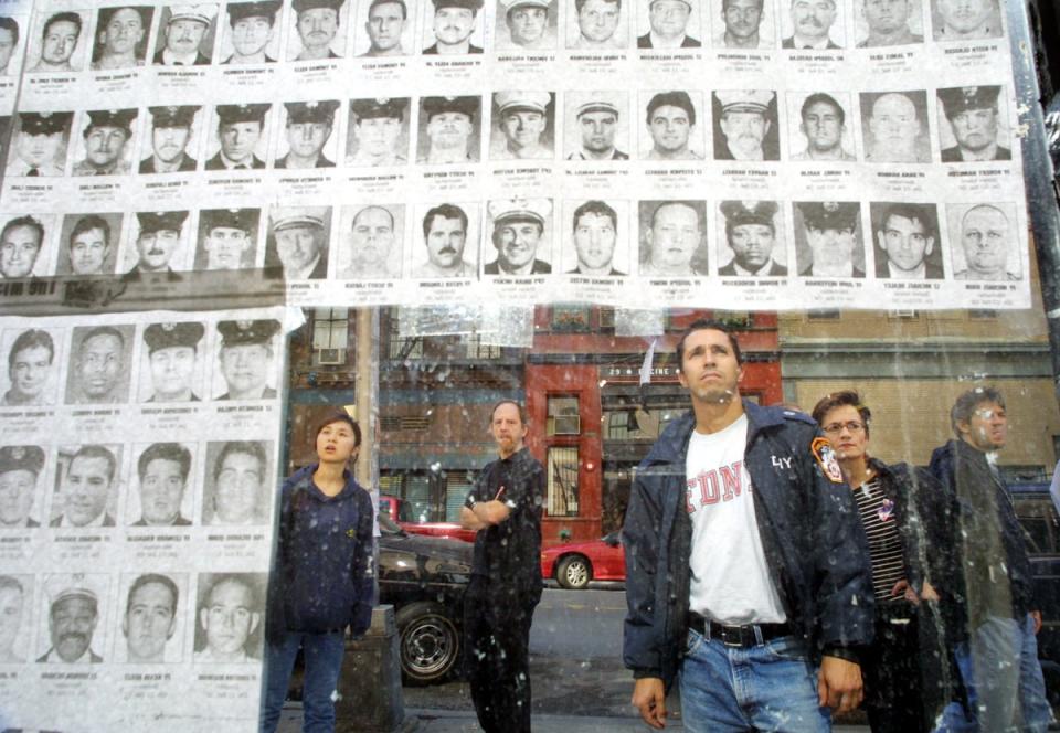 Pedestrians look at photos of missing police and fire personnel missing  a couple of weeks after the attacks (Getty)