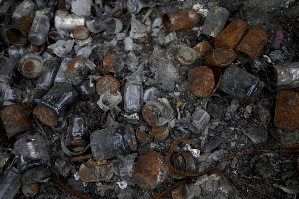 Cans of food lay next to a wreckage of a burned out van that triggered an anti-tank mine, killing its three occupants, lies by the side of a dirt track in Andriyivka, on the outskirts of Kyiv, Ukraine, Tuesday, June 14, 2022. Russia’s invasion of Ukraine is spreading a deadly litter of mines, bombs and other explosive devices that will endanger civilian lives and limbs long after the fighting stop. (AP Photo/Natacha Pisarenko)