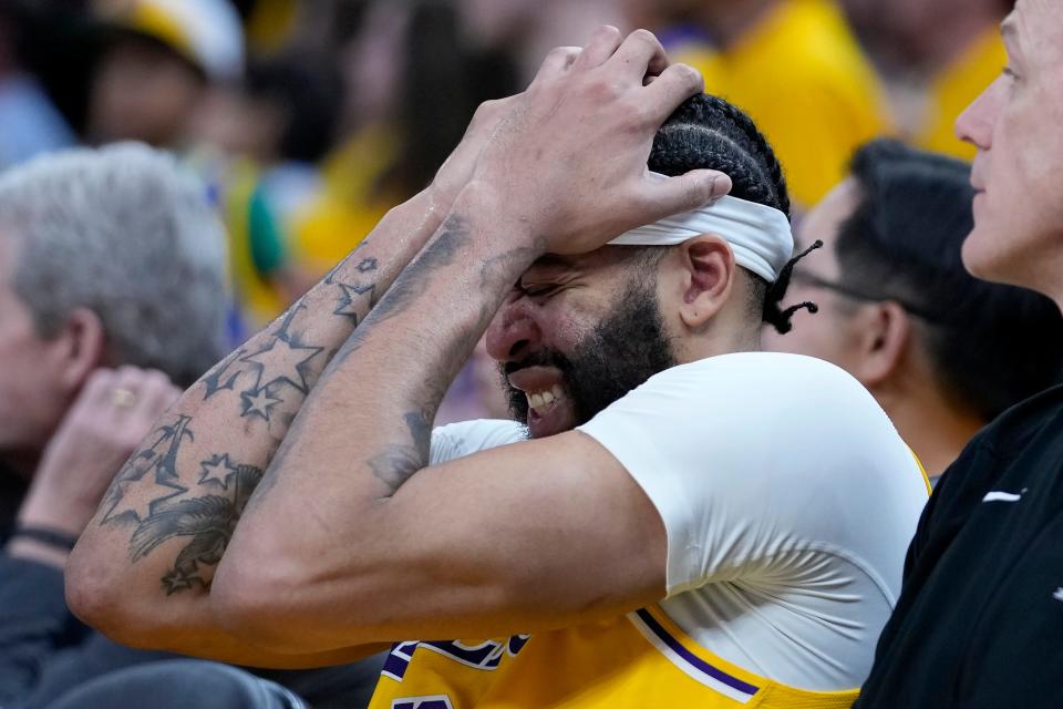 Lakers big man Anthony Davis holds his head on the bench during the second half of Game 5 against the Warriors.