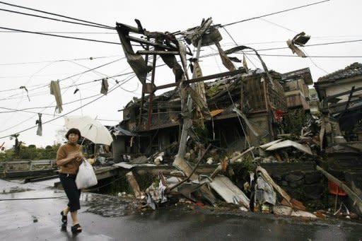 A woman walks past collapsed houses after a tornado swept through a residential area of Tsukuba city in Ibaraki prefecture, north east of Tokyo. Rescue workers rushed 15 people to hospital immediately6 after the tornado