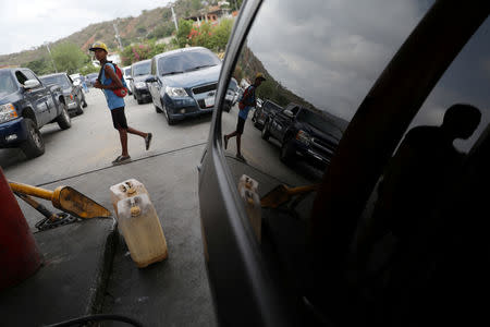 A man walks past fuel containers while vehicle queue to refuel with gasoline in Puerto Cabello, Venezuela May 17, 2019. REUTERS/Manaure Quintero/Files