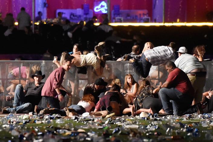 People scramble for shelter at the Route 91 Harvest country music festival after apparent gun fire was heard on October 1, 2017 in Las Vegas, Nevada. A gunman has opened fire on a music festival in Las Vegas, leaving at least 20 people dead and more than 100 injured. Police have confirmed that one suspect has been shot. The investigation is ongoing.