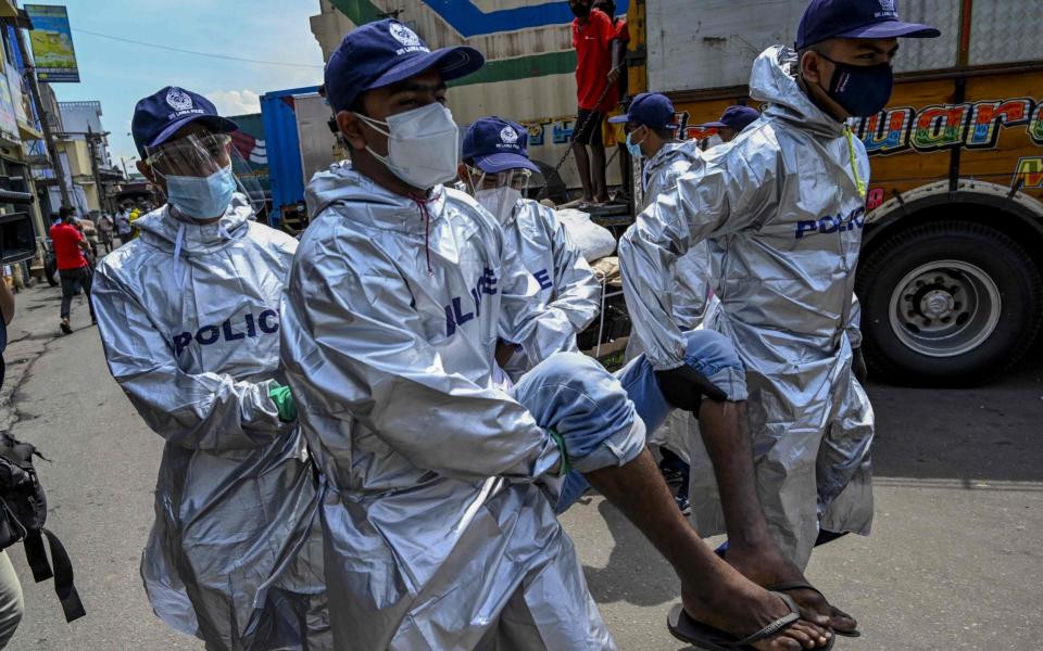 Policemen arrest a man for not wearing a face mask in Colombo - ISHARA S. KODIKARA / AFP