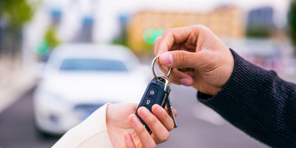 two hands exchanging keys after trading in a car at a dealership