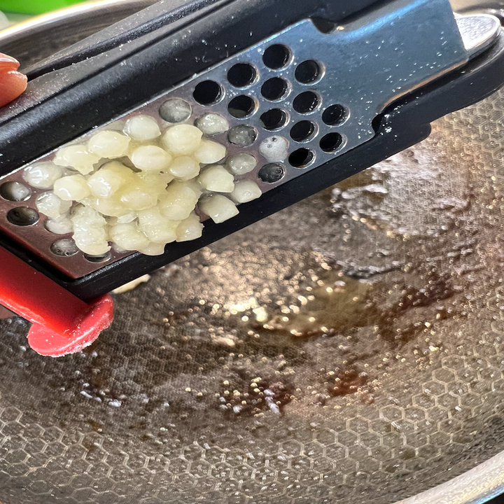 Garlic being minced into the pan