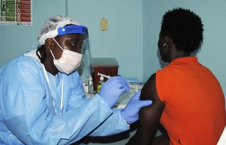 A health worker injects a woman with an Ebola vaccine during a trial in Monrovia, February 2, 2015. REUTERS/James Giahyue