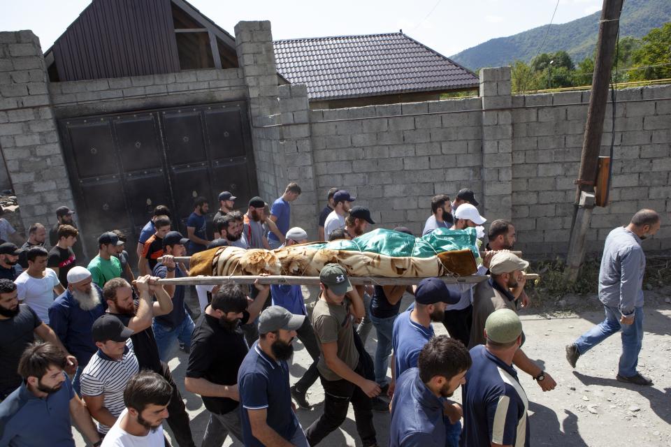 FILE-In this Aug. 29, 2019 file photo people carry the body of the victim who has been identified as Zelimkhan Khangoshvili, a Georgian Muslim during the funeral in Duisi village, the Pankisi Gorge valley, in Georgia. Germany’s foreign ministry says it has expelled two Russian diplomats after prosecutors announced they suspected Moscow’s involvement in the brazen daylight slaying of a Georgian man in Berlin. (AP Photo/Zurab Tsertsvadze)