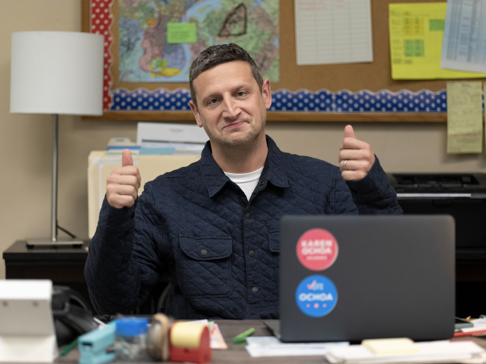 A man gives a thumbs up to the camera while frowning