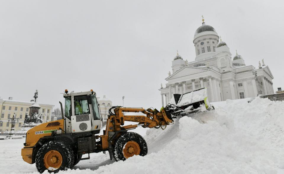 A snow plough works to remove snow at the Senate Square near the Helsinki Cathedral, in Helsinki, Sunday Jan. 30, 2022. A winter storm brought heavy winds and snow on Saturday and Sunday to Finland. (Heikki Saukkomaa/Lehtikuva via AP)