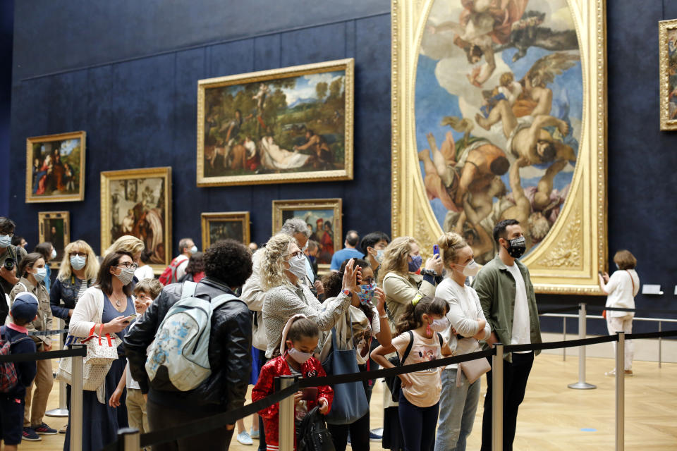 Visitors watch the Leonardo da Vinci's painting Mona Lisa, in Paris, Monday, July 6, 2020. The home of the world's most famous portrait, the Louvre Museum in Paris, reopened Monday after a four-month coronavirus lockdown. (AP Photo/ Thibault Camus)