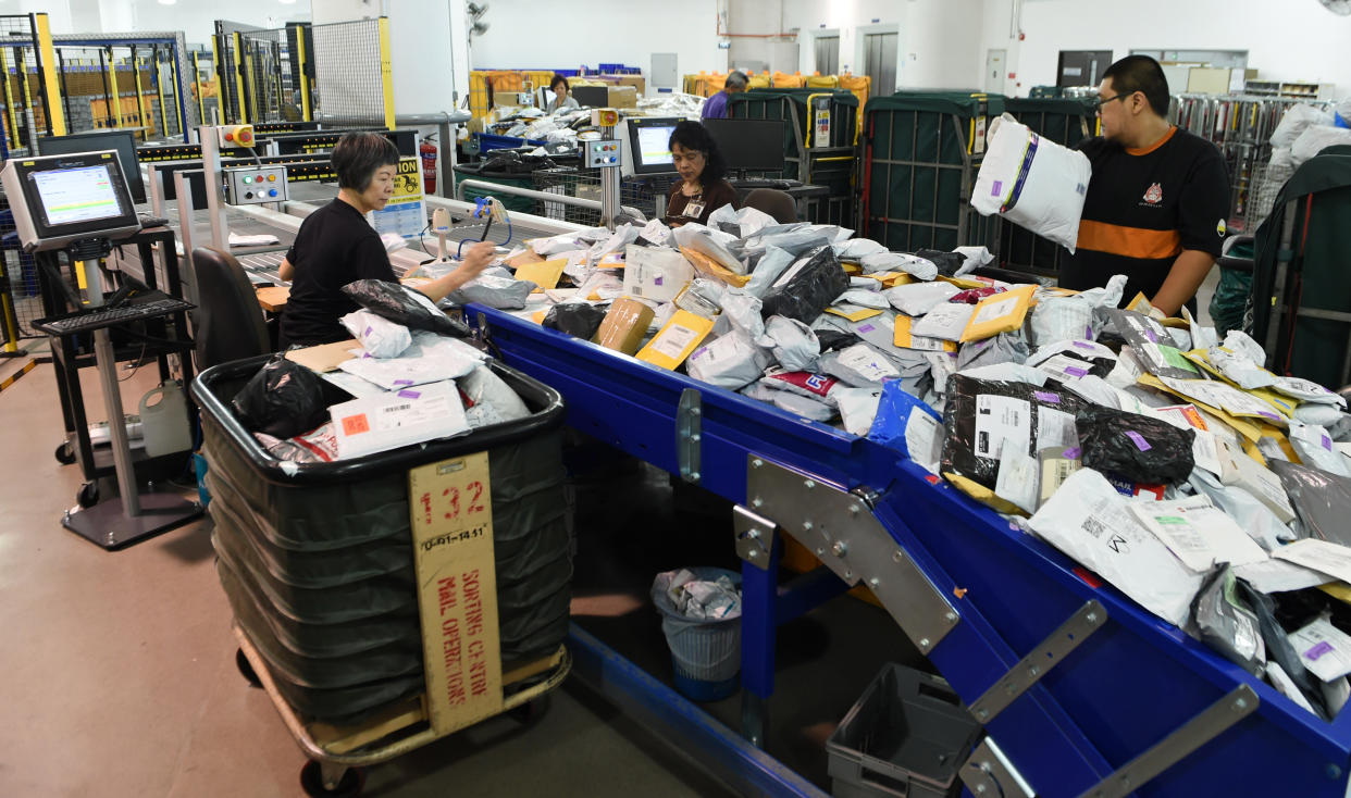 This photograph taken on January 12, 2016 shows employees of SingPost sorting out parcels at its centre in Singapore. SingPost was founded as the Singapore Post Office in 1819 shortly after Sir Stamford Raffles established the island as a British colony. SingPost, whose home market is just 5.5 million-strong, in 2003 decided to transform itself into an e-commerce and logistics company. / AFP / ROSLAN RAHMAN        (Photo credit should read ROSLAN RAHMAN/AFP via Getty Images)