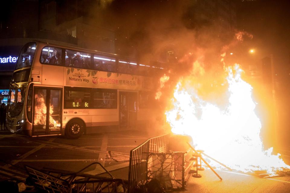 Passengers look out from a bus at a burning barricade lit by pro-democracy protesters. (Getty Images)