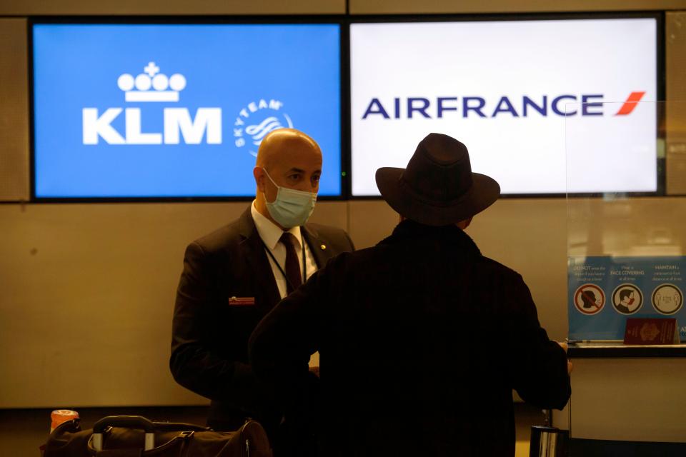 An employee wears a face mask as a passenger checks-in for a flight at the Air France and KLM counter inside the Tom Bradley International Terminal (TBIT) at Los Angeles International Airport (LAX) amid increased Covid-19 travel restrictions on January 25, 2021 in Los Angeles, California. - President Joe Biden will re-impose a Covid-19 travel ban on most non-US citizens who have been in Britain, Brazil, Ireland and much of Europe, a White House official said, as the new administration ramps up its pandemic response. (Photo by Patrick T. FALLON / AFP) (Photo by PATRICK T. FALLON/AFP via Getty Images)