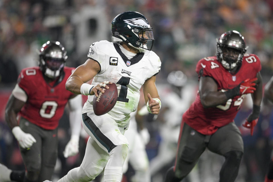 Philadelphia Eagles quarterback Jalen Hurts (1) scrambles as Tampa Bay Buccaneers linebacker Yaya Diaby (0) and defensive tackle Calijah Kancey (94) chase him during the second half of an NFL wild-card playoff football game, Monday, Jan. 15, 2024, in Tampa, Fla. (AP Photo/Phelan M. Ebenhack)