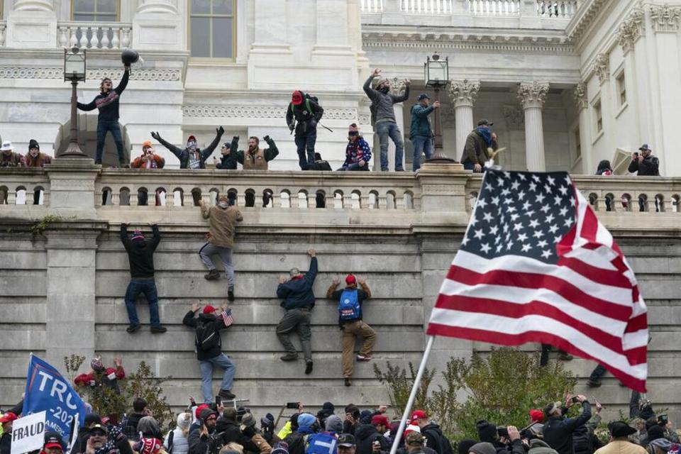 Alborotadores escalan un muro en el Capitolio de Estados Unidos el 6 de enero de 2021, en Washington.