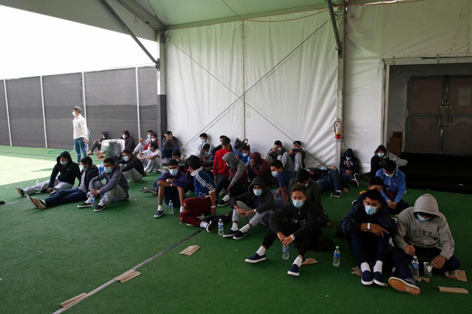 Minors who tested positive for Covid-19 sit on the ground at the Department of Homeland Security holding facility run by the Customs and Border Patrol (CBP) on March 30, 2021 in Donna, Texas. The Donna location is the main detention center for unaccompanied children coming across the U.S. border in the Rio Grande Valley.