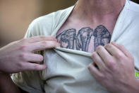 En esta imagen, tomada el 13 de enero de 2020, el cuidador Marcos Flores muestra un tatuaje en su pecho durante una entrevista cerca del recinto de Mara, una ejemplar de elefante asiático, en el antiguo zoo conocido como Ecopark, en Buenos Aires, Argentina. Mara dejará el recinto y será trasladada a un santuario de elefantes en Brasil, pero antes de su viaje al país vecino, que se espera para el mes de marzo, la elefanta, de 55 años, se está entrenando para prepararse para su confinamiento durante el viaje de 2.500 kilómetros por carretera, que durará entre dos y tres días. (AP Foto/Daniel Jayo)