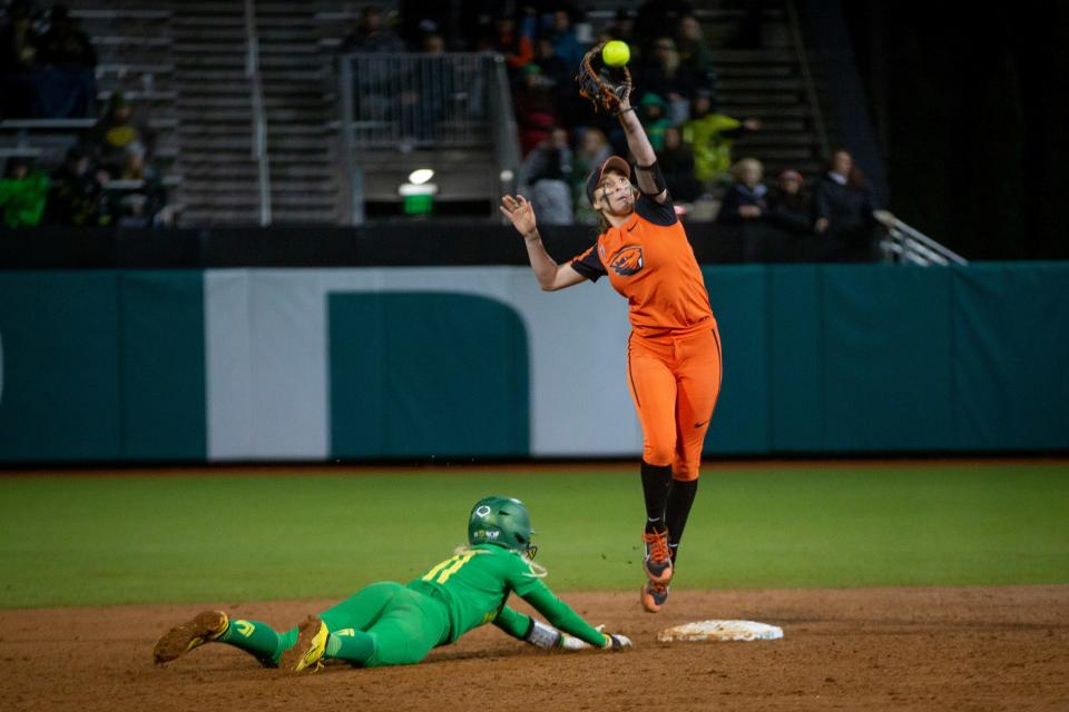 Oregon catcher Terra McGowan dives safely back to second base as Oregon State's Savanah Whatley leaps to make a catch at second during a win over Oregon State Saturday, April 30, 2022, in Eugene.