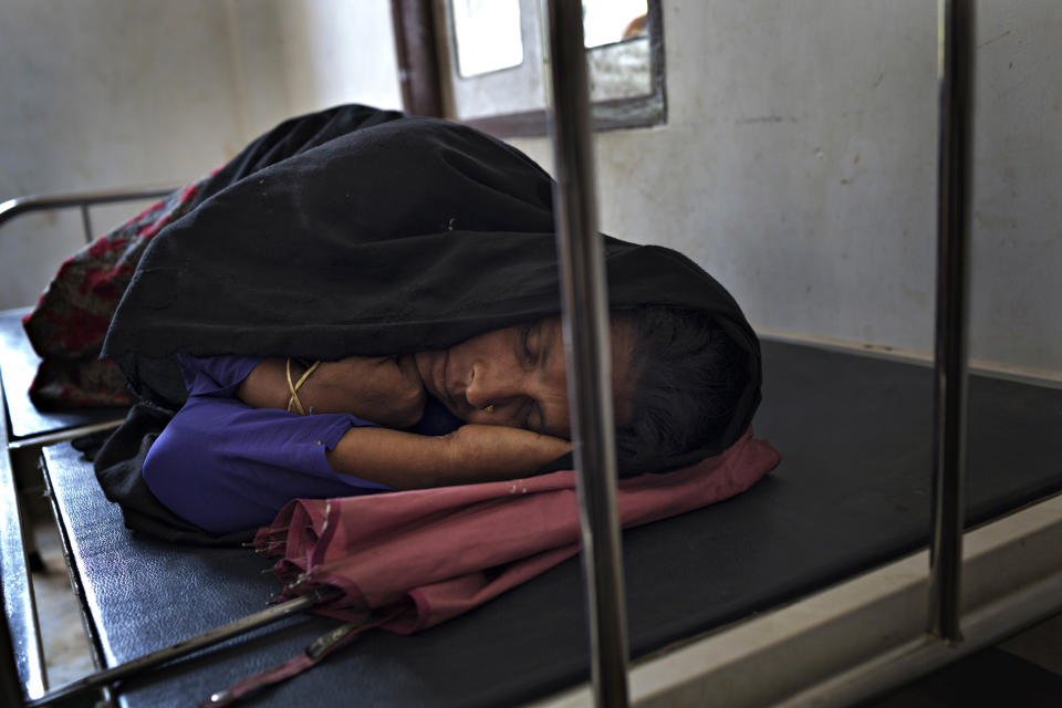 SITTWE, BURMA - MAY 06: A woman sleeps while she waits to be treated at a clinic in the Dar Paing refugee camp on May 6, 2014 in Sittwe, Burma. Some 150,000 Rohingya IDP (internally displaced people) are currently imprisoned in refugee camps outside of Sittwe in Rakhine State in Western Myanmar. Medecins Sans Frontieres (MSF), the primary supplier of medical care within the camps, was banned in March by the Myanmar government. Follow up attacks by Buddhist mobs on the homes of aid workers in Sittwe put an end to NGO operations in the camps. Though some NGOs are beginning to resume work, MSF remains banned, and little to no healthcare is being provided to most Rohingya IDPs. One Rohingya doctor is servicing 150,000 refugees with limited medication. Several Rakhine volunteer doctors sporadically enter the camps for two hours a day. Births are the most complicated procedures successfully carried out in the camps, requests to visit Yangon or Sittwe hospitals for life threatening situations require lengthy applications and are routinely denied. Malnutrition and diarrhea are the most widespread issues, but more serious diseases like tuberculosis are going untreated and could lead to the rise of drug resistant tuberculosis (DR-TB).  (Photo by Andre Malerba/Getty Images)