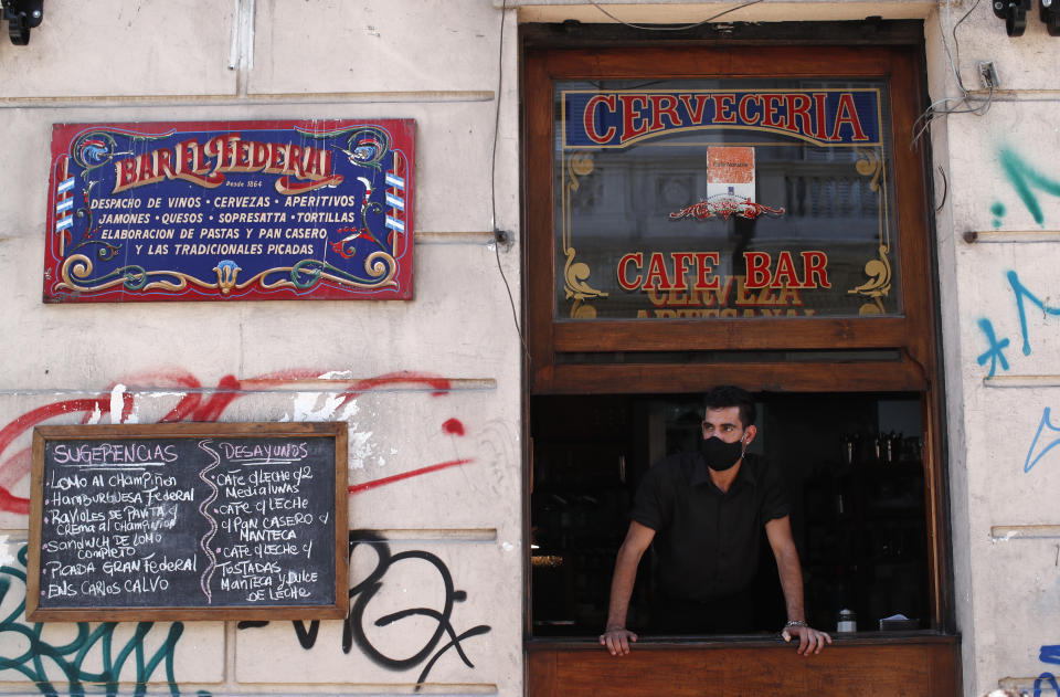 Waiter Federico Alfredo Giana stands at a window of the El Federal Bar in Buenos Aires, Argentina, Tuesday, Nov. 10, 2020. New coronavirus pandemic measures have forced El Federal to reduce its previous capacity of 80 customers to 15, and its owner said that November’s revenue was 85% less than in the same month last year. (AP Photo/Natacha Pisarenko)