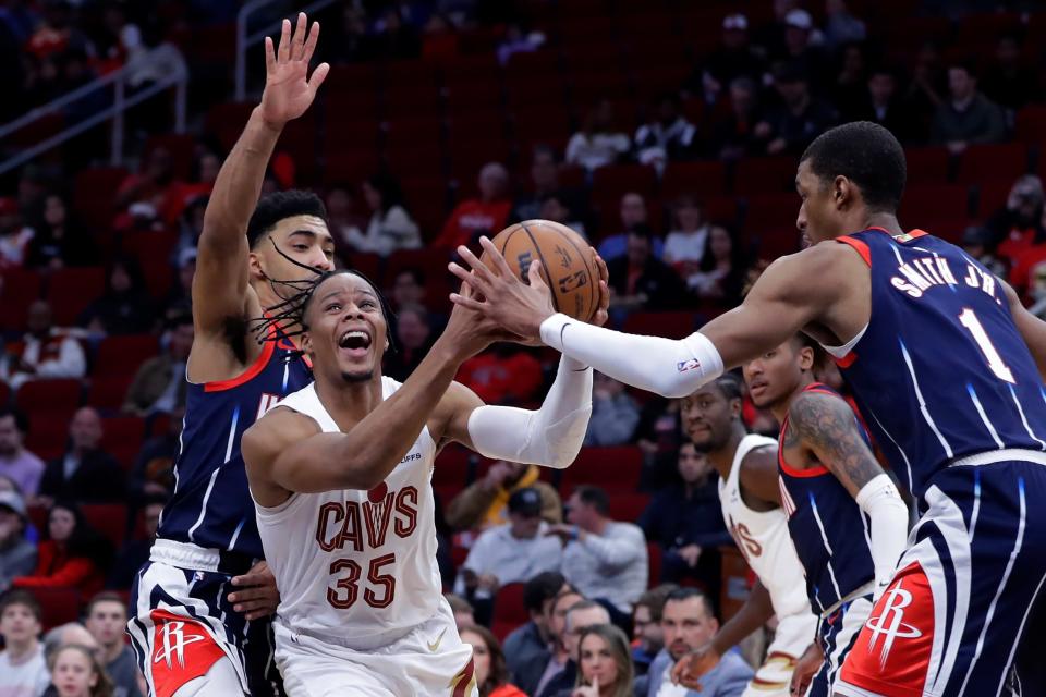 Cleveland Cavaliers forward Isaac Okoro (35) drives between Houston Rockets forwards K.J. Martin, left, and Jabari Smith Jr. (1) during the first half of an NBA basketball game Thursday, Jan. 26, 2023, in Houston. (AP Photo/Michael Wyke)