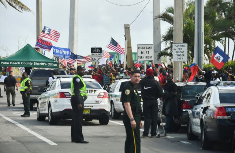 Protesters waving the national flag of Haiti (R) look on near supporters of US President Donald Trump (L) as the president's motorcade drives by in West Palm Beach, Florida