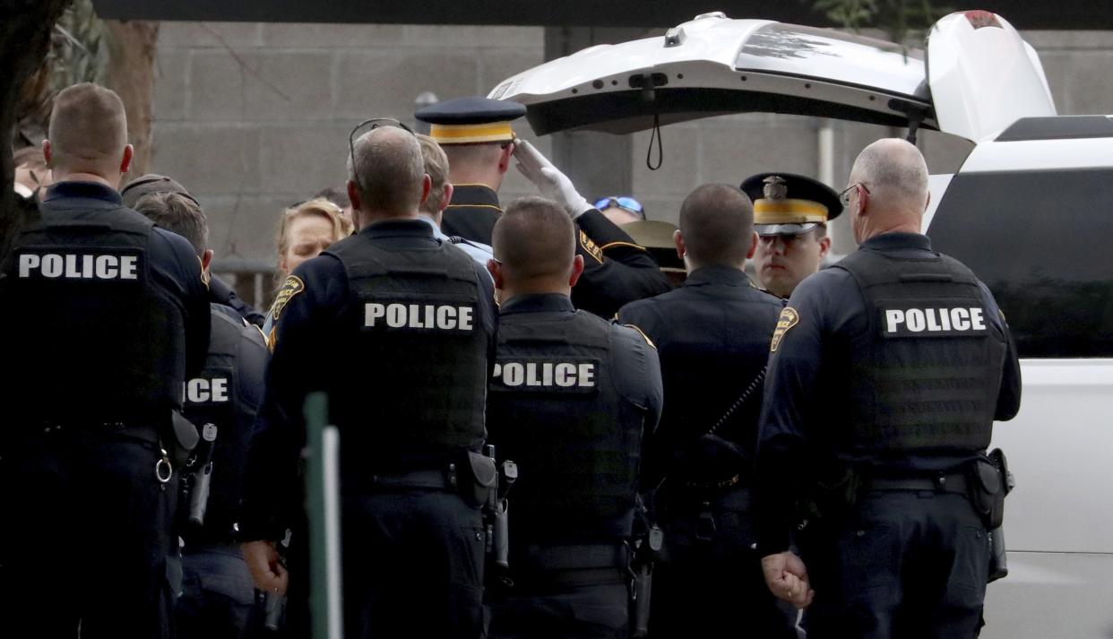 Tucson Police officers stand with an an honor guard as the body of Pima County Constable Deborah Martinez is loaded into a Pima County Medical Examiner van.