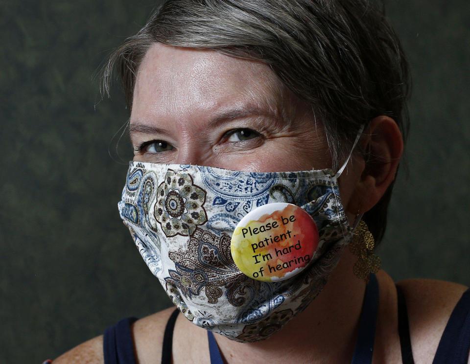 Amy Bull, who is hard of hearing, wears a button on her mask that tells people.