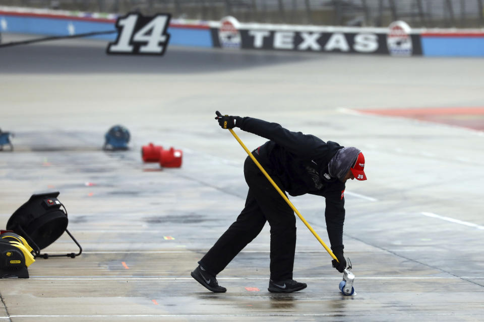 A member of Erik Jones pit crew squeegees water out of the pit area as crews prepare to resume a NASCAR Cup Series auto race at Texas Motor Speedway in Fort Worth, Texas, Tuesday, Oct. 27, 2020. The race was stopped on Sunday because of drizzle and misty conditions that allowed drivers to complete just 52 of 334 laps. Another 115 laps have to be completed to get to the halfway mark of 167 laps that would make Texas an official race.. (AP Photo/Richard W. Rodriguez)