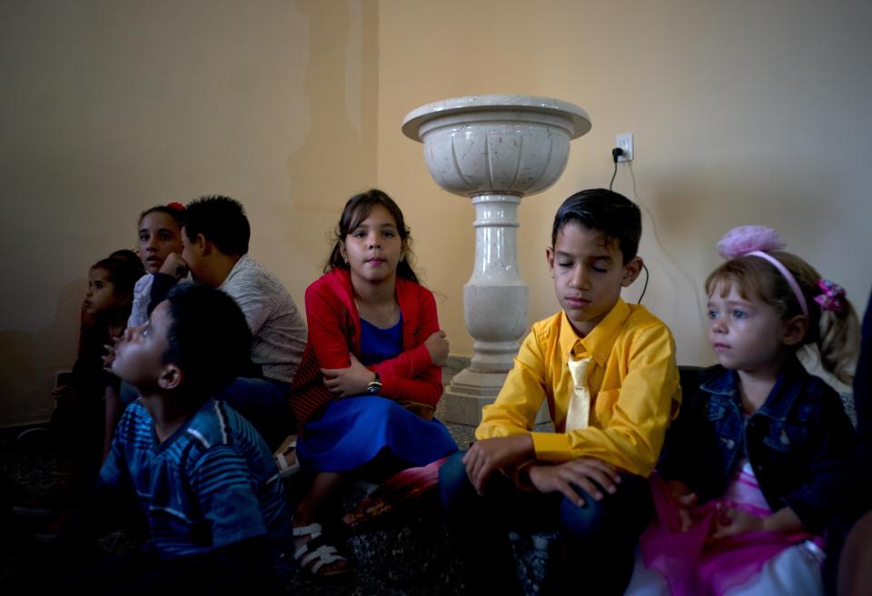 Children sit next to a baptismal font as they wait for the start of a consecration Mass of the Sagrado Corazon de Jesus, or Sacred Heart, Catholic church, in Sandino, Cuba, Saturday, Jan. 26, 2019. The church is one of three Catholic churches that the Cuban government authorized to be built, and the first one to be completely finished with the help of Tampa's St. Lawrence Catholic Church in Florida. (AP Photo/Ramon Espinosa)