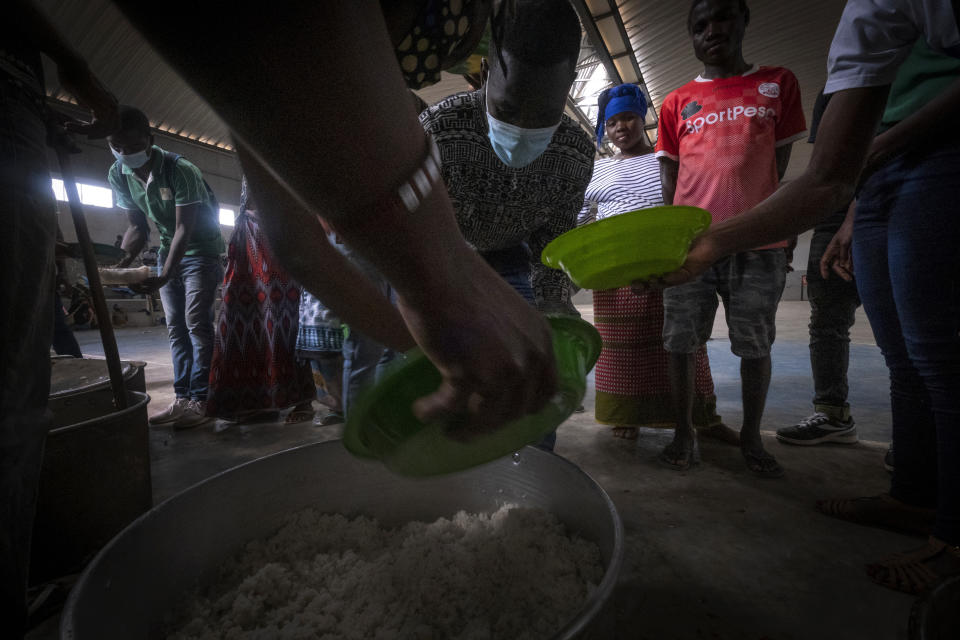 Volunteers from a local NGO distribute food at a municipal pavilion where refugees are sheltered in Pemba, Mozambique, after they fled attacks in Palma in Northern Mozambique, Monday April 19, 2021. The damage caused by Mozambique's extremist rebels in their deadly assault on the northeastern town of Palma continues to be assessed. More than three weeks after the rebels launched a three-pronged attack, which lasted at least five days, Mozambican police and relief agencies are working to help the thousands uprooted by the violence and restore the town to daily life.(AP Photo)