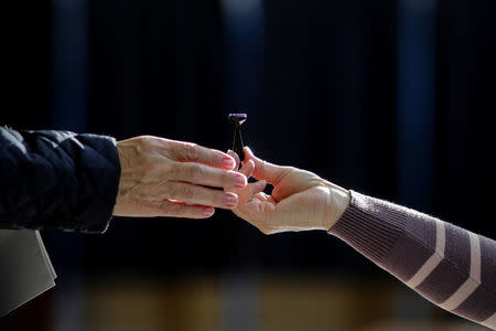 An official hands out a stamp to a voter during the process of the parliamentary elections, in Bucharest, Romania December 11, 2016. Inquam Photos/Octav Ganea/via REUTERS