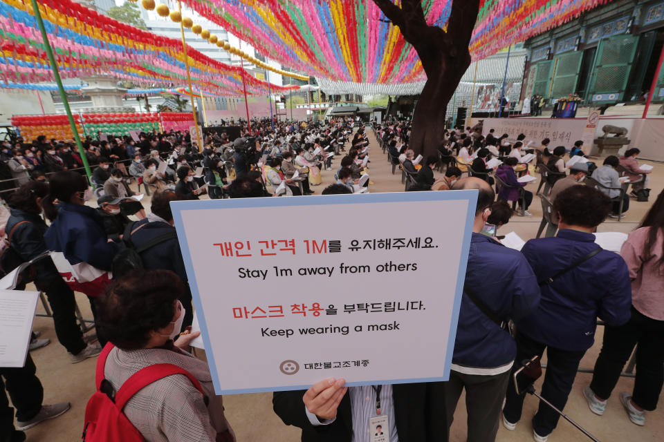 A Buddhist believer holds a notice about precautions against the new coronavirus during a service to pray for overcoming the COVID-19 outbreak and to celebrate Buddha's birthday at the Chogyesa temple in South Korea, Thursday, April 30, 2020. (AP Photo/Ahn Young-joon)