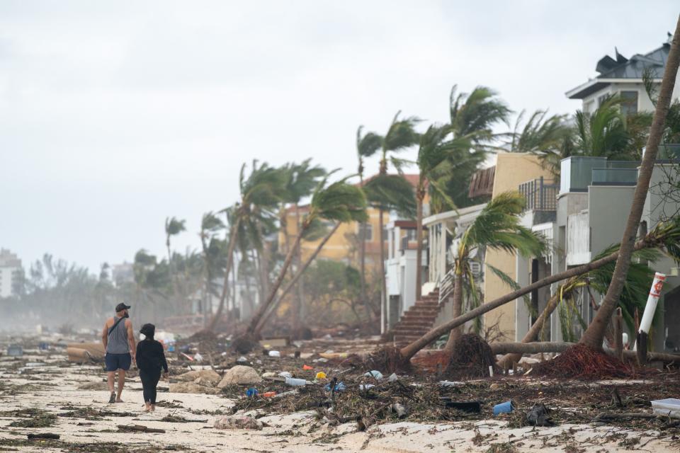 BONITA SPRINGS, FL - SEPTEMBER 29: People walk along the beach looking at property damaged by Hurricane Ian on September 29, 2022 in Bonita Springs, Florida. The storm made a U.S. landfall on Cayo Costa, Florida, and brought high winds, storm surges, and rain to the area causing severe damage. (Photo by Sean Rayford/Getty Images)