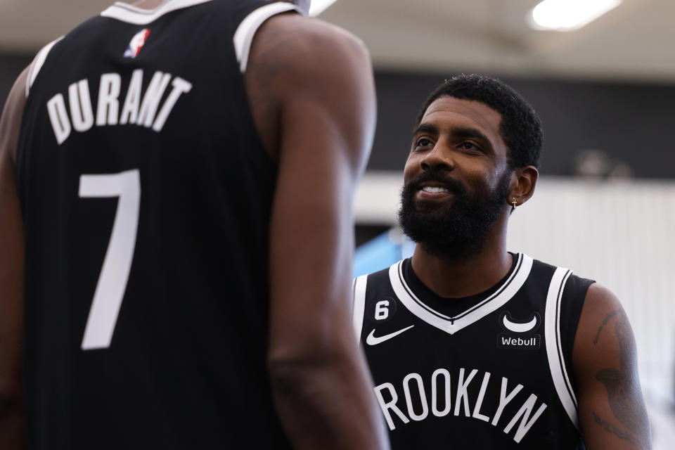 Brooklyn Nets guard Kyrie Irving speaks with Kevin Durant as he walks to the podium for a news conference at Nets media day on Sept. 26, 2022. (Dustin Satloff/Getty Images)