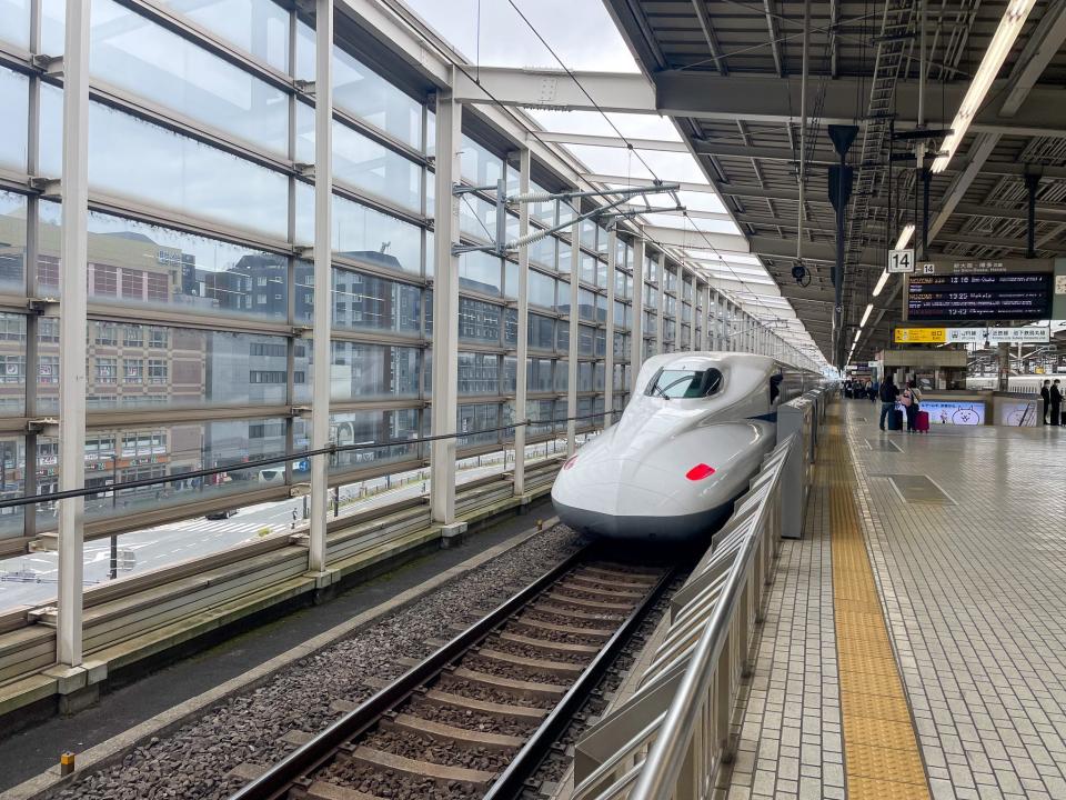 A bullet train pulls into a train station.