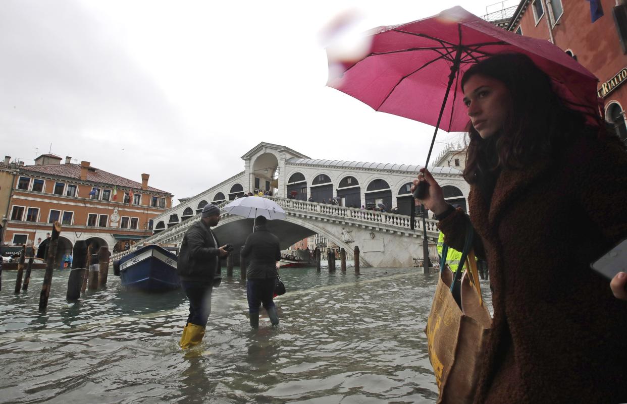 People walk near the Rialto bridge on the occasion of a high tide, in Venice, Italy, Tuesday, Nov. 12, 2019. (Photo: Luca Bruno/AP)