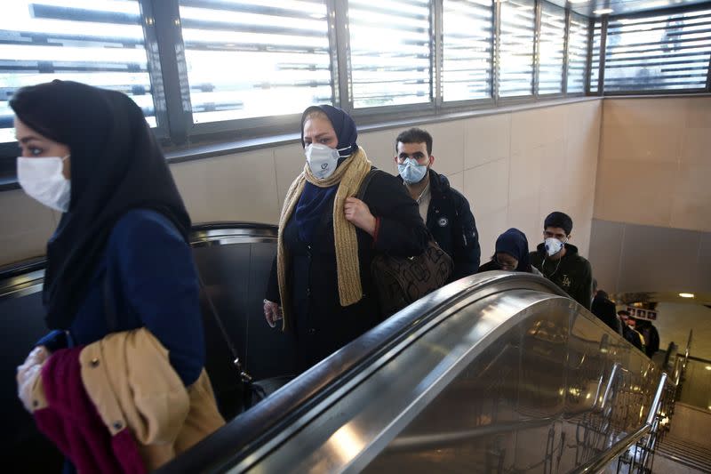 Iranian people wear protective masks to prevent contracting a coronavirus, as they climb an escalator in Tehran