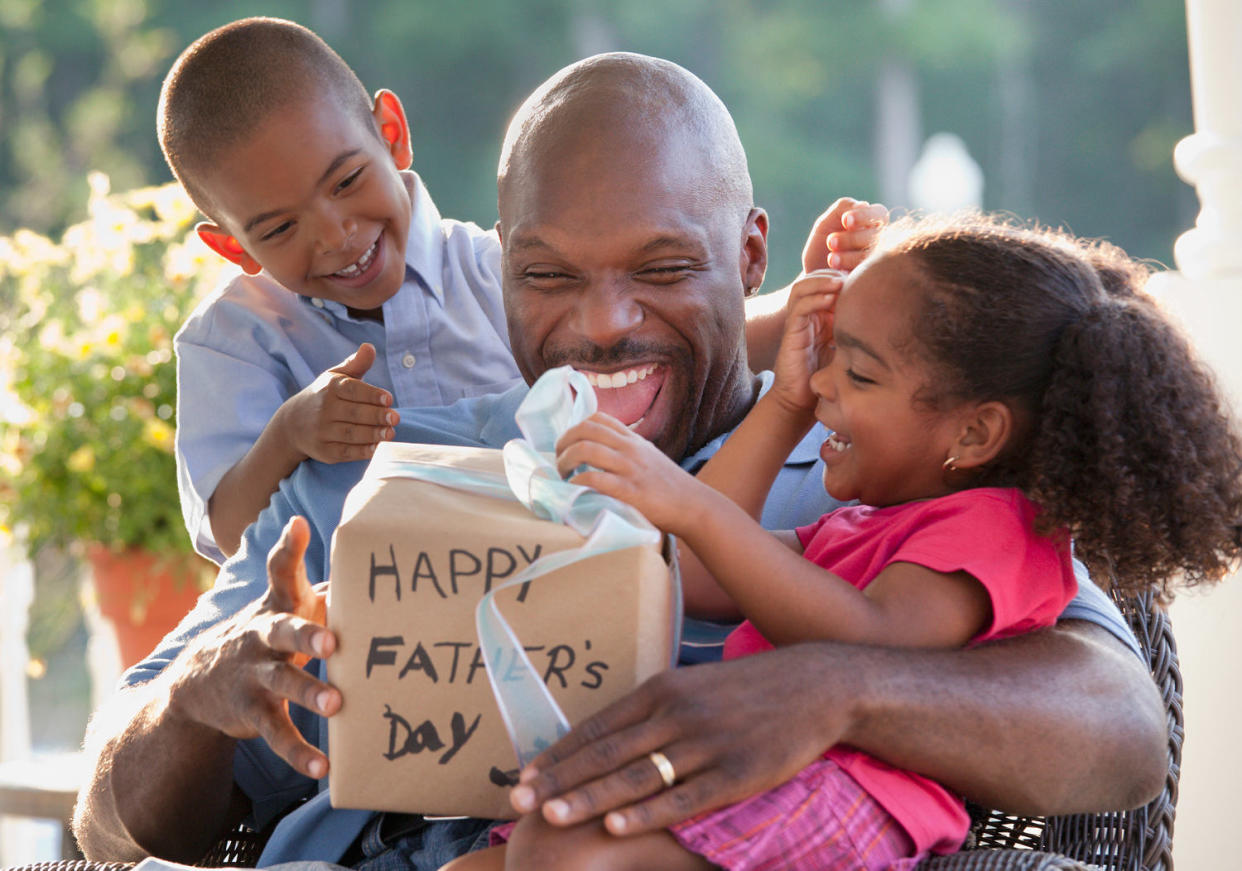 dad opening father's day gifts with kids on lap (Getty Images)